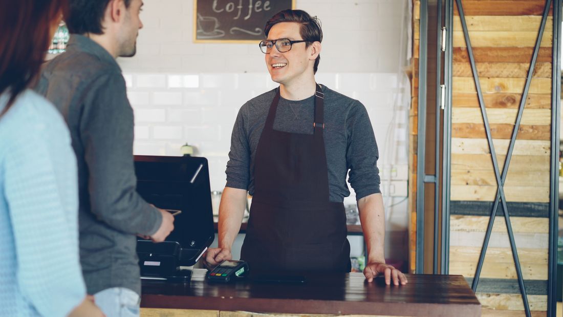 A barista assisting customers at a real café counter